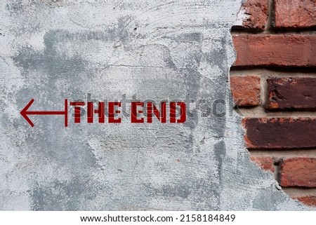 Old brick wall with text and direction to THE END, means final part of something, finish in period of time, to finish or stop story or relationship