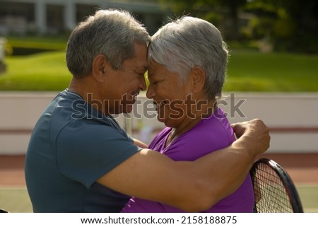Close-up of happy biracial senior couple with eyes closed and face to face romancing at tennis court. romance, unaltered, sport, togetherness, love, retirement, healthy and active lifestyle concept. Royalty-Free Stock Photo #2158188875