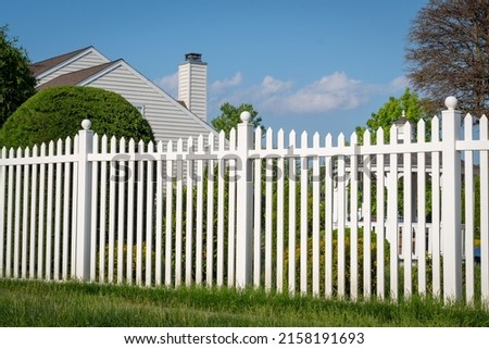 White vinyl fence in a cottage village tall thuja bushes behind the fence fencing of private property grass plastic Royalty-Free Stock Photo #2158191693