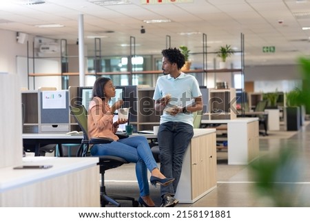 Young biracial colleagues discussing while eating lunch together in cubicle at modern workplace. unaltered, business, food, teamwork and modern office concept. Royalty-Free Stock Photo #2158191881