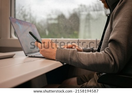 A male traveler works online on a European train while traveling by train. Unrecognizable man. High quality photo