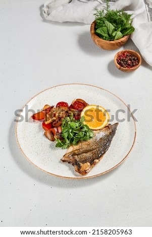 Fish dish - roasted dorado fillet with vegetables. Grilled fish fillet and roasted paprika, tomatoes and onion. Roast dorado fillet with garnish, greens and lemon on ceramic plate Royalty-Free Stock Photo #2158205963
