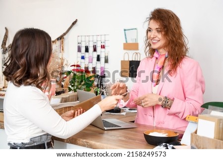 Female business owner serving client in her shop