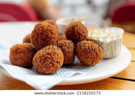 Bitterballen, Dutch meat-based snack in white plate served with mustard on wooden tabel background, Typically containing a mixture of beef or veal, Bitterballen are one of Holland's favorite snacks. Royalty-Free Stock Photo #2158250173