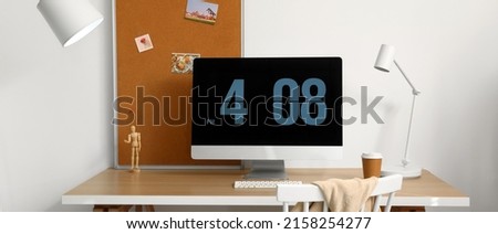 Workplace with modern computer and lamp near light wall
