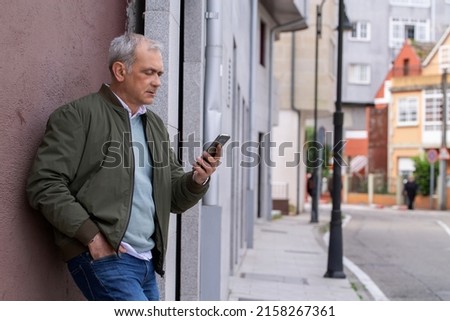 adult man on the street checking and reading the messages on the smartphone