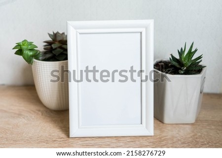 Portrait white picture frame mockup with white pots with succulents and zamiokulkas 