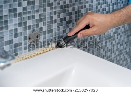 dirty grouts in the bathroom and moldy tiles. master cleans dirt with a tool. Royalty-Free Stock Photo #2158297023
