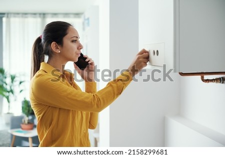 Worried woman calling a boiler breakdown emergency service using her smartphone Royalty-Free Stock Photo #2158299681
