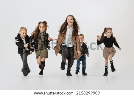 Joy, fun. Happy school and preschool age children, girls and boys running, jumping isolated on grey studio background. Beauty, kids fashion, ad, education, happy childhood concept.