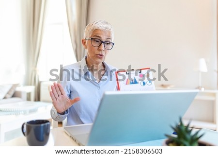 Mature businesswoman presenting charts and graphs on video call online. business, technology and people concept, businesswoman with papers having video conference by laptop computer at office