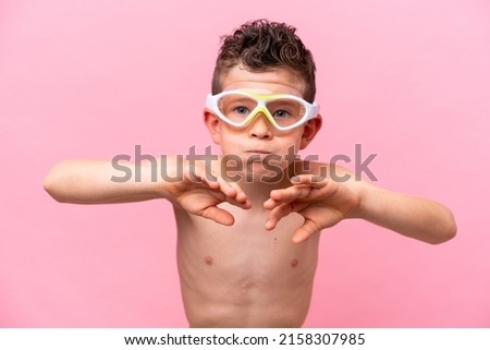 Little caucasian boy wearing a diving goggles isolated on pink background