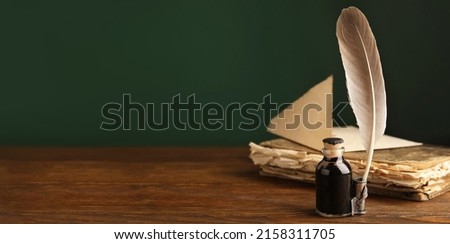 Quill, bottle of ink and old book on wooden table, space for text. Banner design Royalty-Free Stock Photo #2158311705