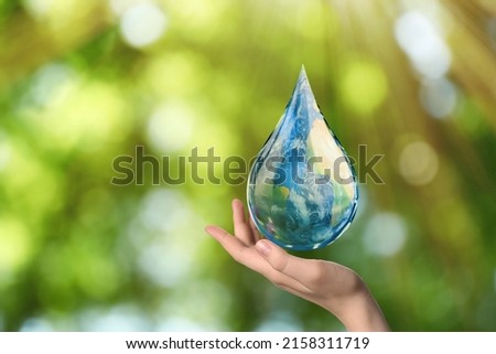 World Water Day. Woman holding icon of drop with Earth image inside on blurred green background, closeup