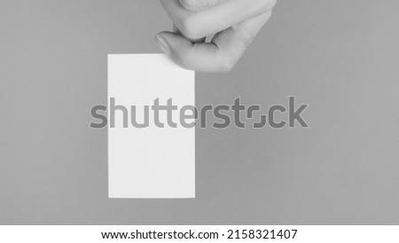 Empty space for text.Male hand holding white blank card isolated on mint green or Tiffany Blue background. black and white picture.