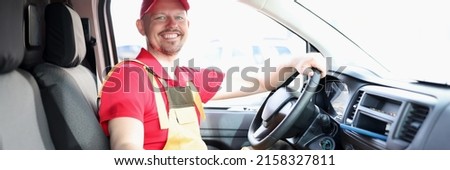 Unshaven male courier sitting in car smiling