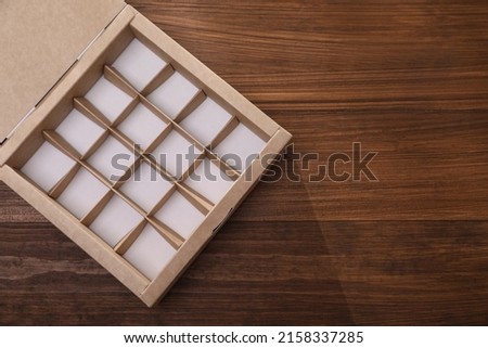 Empty packaging box with dividers on wooden table, top view. Space for text