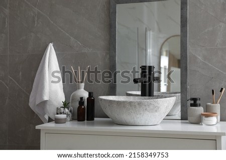 Stone vessel sink with faucet and toiletries on white countertop in bathroom Royalty-Free Stock Photo #2158349753