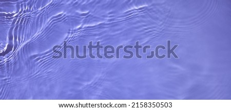 Transparent purple clear water surface texture with ripples and splashes. Abstract summer banner background Water waves in sunlight, copy space, top view. Cosmetic moisturizer micellar toner emulsion Royalty-Free Stock Photo #2158350503