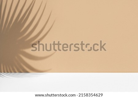 Minimal abstract background with shadow of tropical palm leaves. Presentation of cosmetic product. Premium podium on pastel light beige wall and white table. Showcase, display case, Front view. Mockup