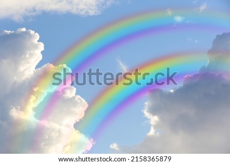 Beautiful view of bright rainbows in blue sky on sunny day