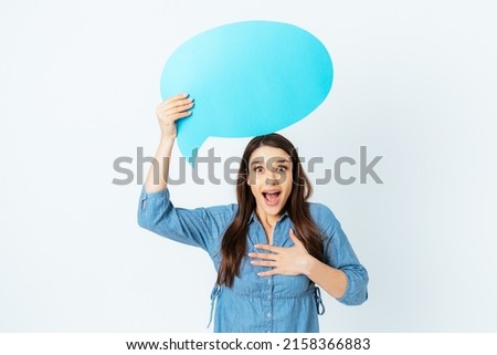 Surprised excited young woman with speech bubble looks at camera amazed