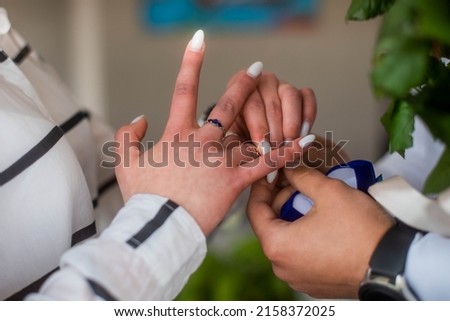 Picture of man putting engagement golden ring on woman hand. Restauraunt background.