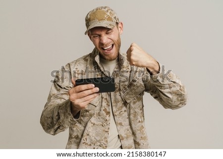 White military man gesturing while playing game on cellphone isolated over white background