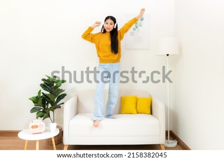 Young smiling woman happy listen music for chill and relax in summer holiday. Lifestyle girl using laptop for entertainment in living room at home.  Lifestyle Concept 