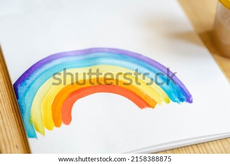 child drawing rainbow on white watercolor paper with place for text