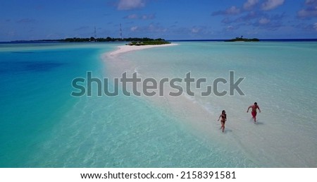 An aerial shot of young couple in beachwear running in water on Rasdhoo Island beach