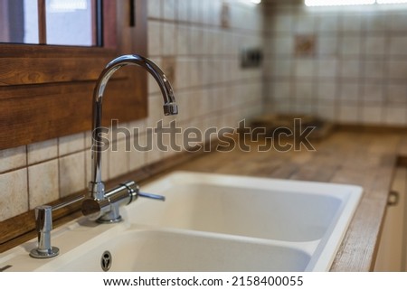 A close-up shot of the white kitchen sink and the tap during daytime with blurred background