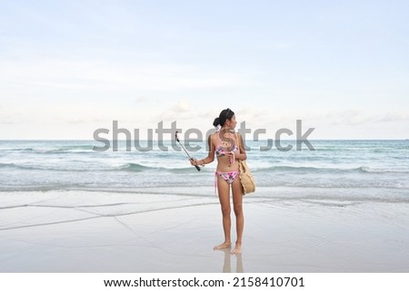 Streamer holding a mobile with a stick while looking distractedly at the sea