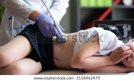 Doctor conducting ultrasound examination of kidneys to child in clinic. Diagnosis of pyelonephritis in children concept Royalty-Free Stock Photo #2158462479