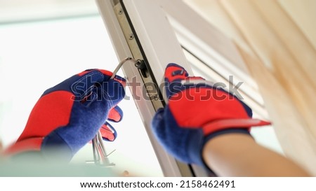 Master in gloves adjusting pvc windows with screwdriver closeup. Installation of plastic windows repair and maintenance concept Royalty-Free Stock Photo #2158462491