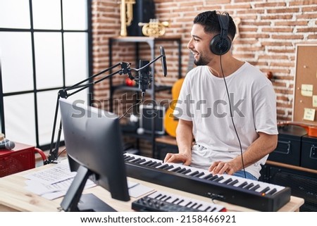 Young arab man musician playing piano keyboard at music studio Royalty-Free Stock Photo #2158466921