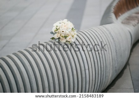 Wedding bouquet of white roses on a bench in the park.