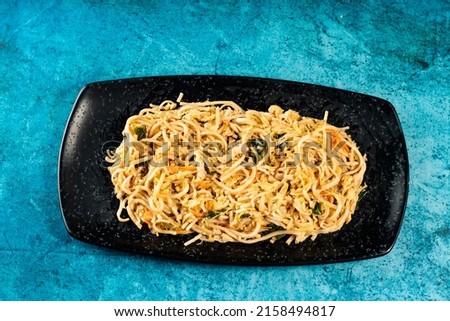 Spicy vegetable chow mein in a black tray isolated on marble background top view of chinese food