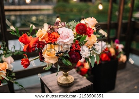 Beautiful flower composition with autumn orange and red flowers and berries. Autumn bouquet in vintage vase on a wooden table  Royalty-Free Stock Photo #2158500351