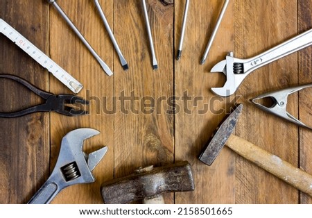 Top view of many tools such as screwdrivers, pliers, wrenches, hammers forming a circle in the centre of the image where there is a copy space. Copy space.
