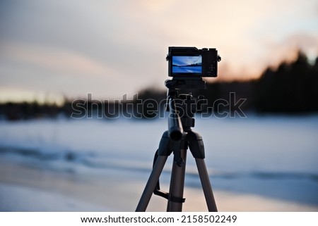 A camera on tripod making time-lapse photography of snow covered landscape in Vantaa