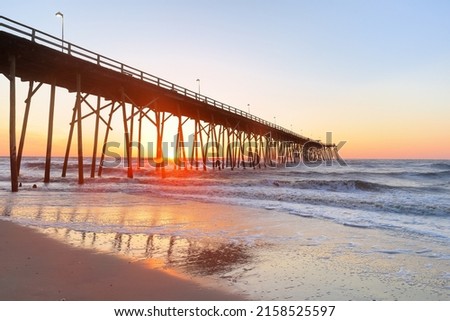 Kure Beach Fishing Pier at sun rise, Kure Beach, North Carolina, USA. Kure beach is the home to the oldest fishing pier on the Atlantic Coast and an oceanfront park. Royalty-Free Stock Photo #2158525597