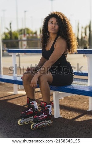 A vertical shot of a beautiful curly woman wearing the rollers skates