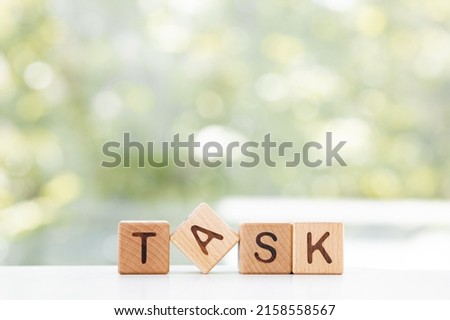 TASK word is made of wooden blocks lying on the table, concept, green summer background