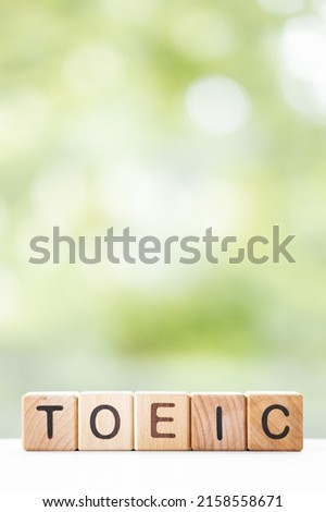 TOEIC - word is written on wooden cubes on a green summer background. Close-up of wooden elements.