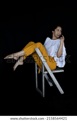 A beautiful Hispanic female sitting on a chair on a blurred background