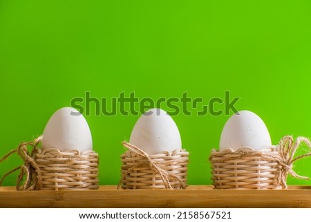 white eggs in small baskets and green background