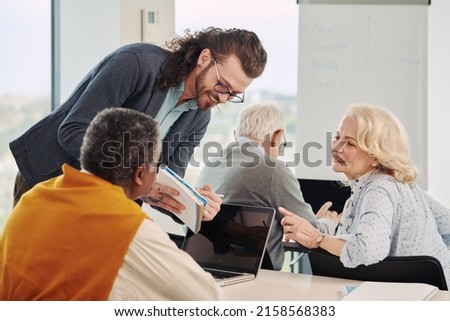Multicultural group of senior students asking questions their tutor who showing them solution. Royalty-Free Stock Photo #2158568383