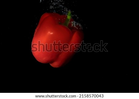 red bell pepper in water with splash on black background  isolated with bubbles