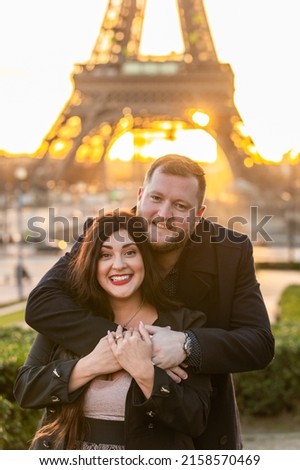 A vertical shot of the happy couple taking pictures with Eiffel Tower on the background, Paris, France